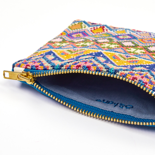 Close up of a pouch with a colourful embroidered pattern, blue zip and a matching blue internal lining..